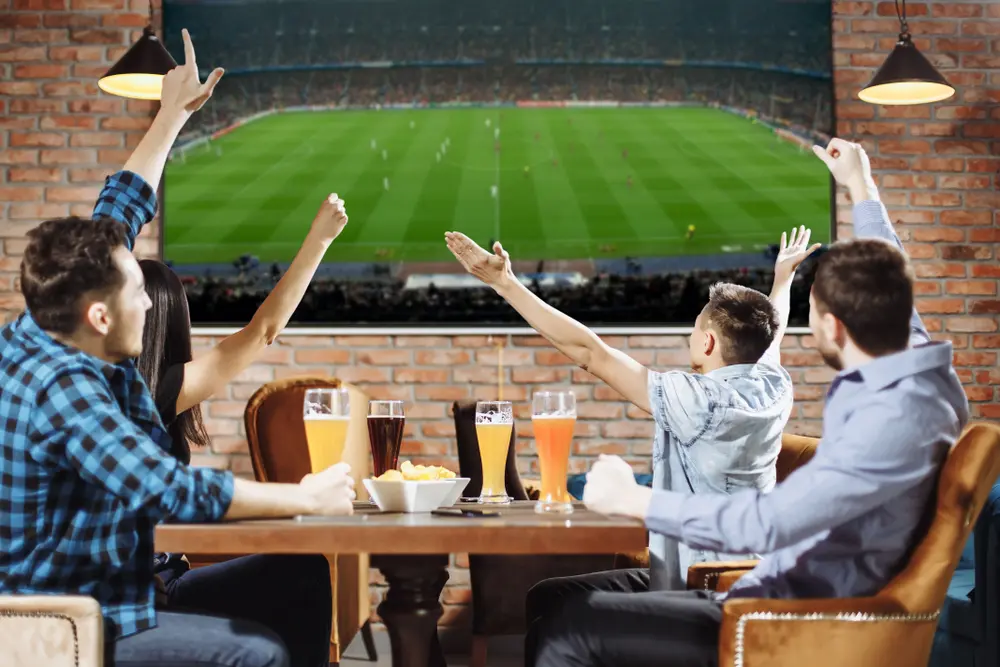 Amigos vêm futebol numa TV gigante num bar com excelentes cores. Micro RGB,OLED vs MIni LED nas cores o Micro RGB ganha